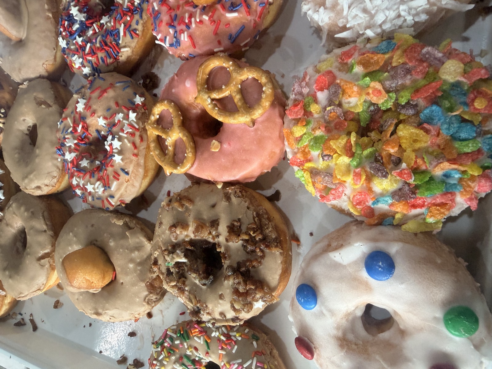 Assorted specialty donuts including coconut, strawberry and cereal-topped