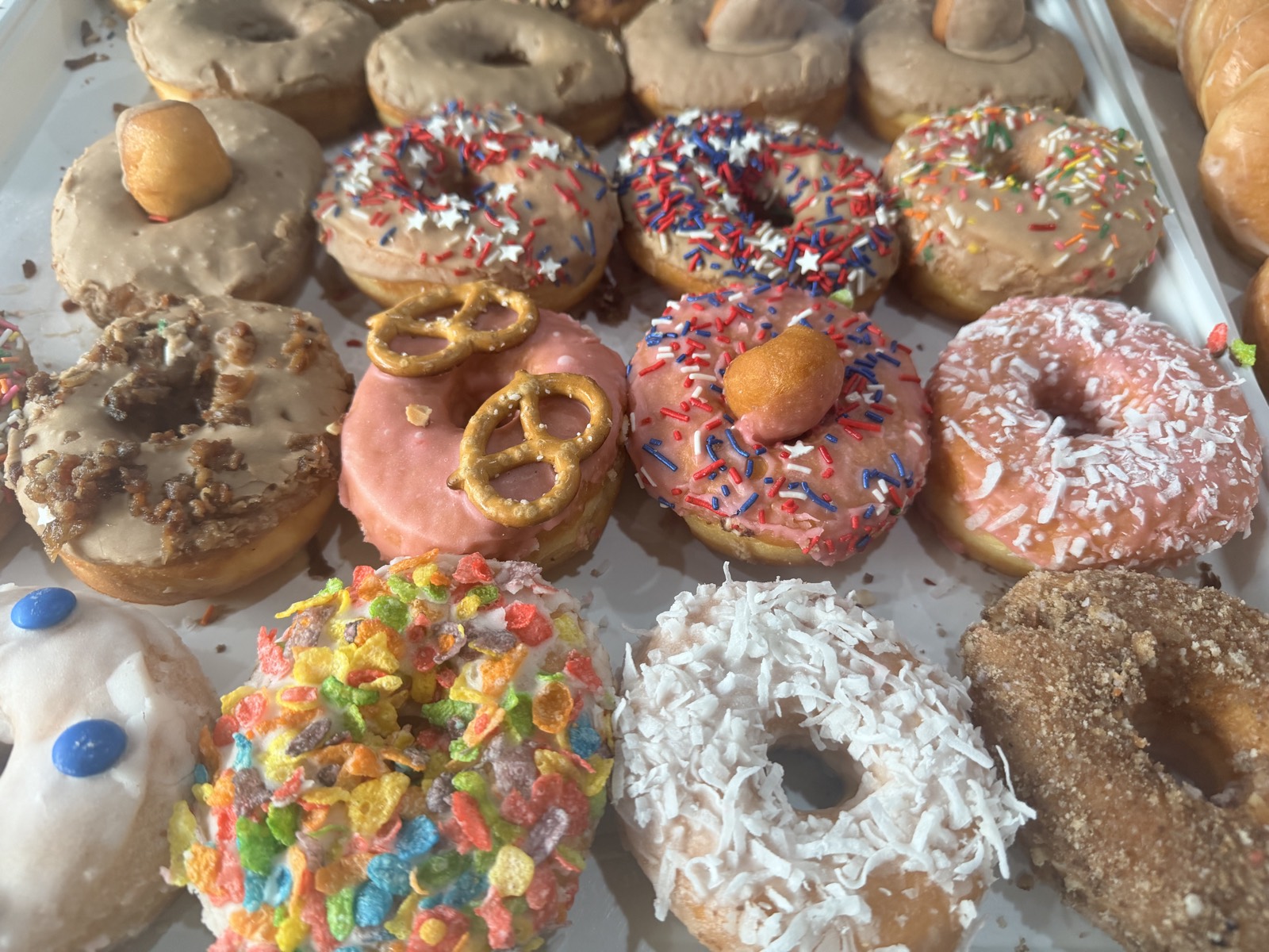 A fresh tray of colorful glazed and specialty donuts at Donuts Pho Bagels in New Bern, NC